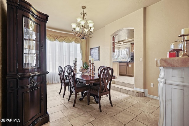 dining area featuring light tile patterned floors, arched walkways, a wealth of natural light, and a chandelier