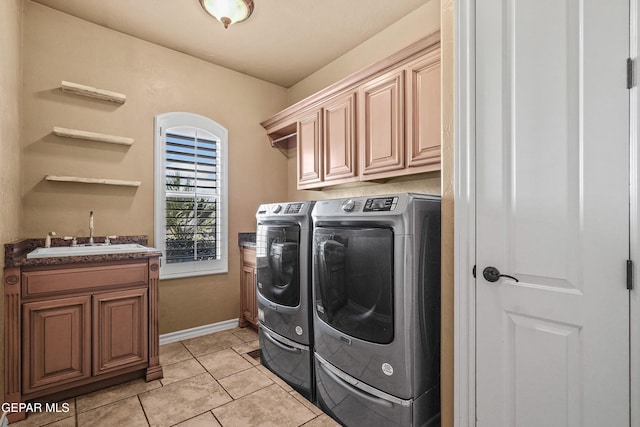 laundry room featuring washing machine and clothes dryer, baseboards, light tile patterned floors, cabinet space, and a sink