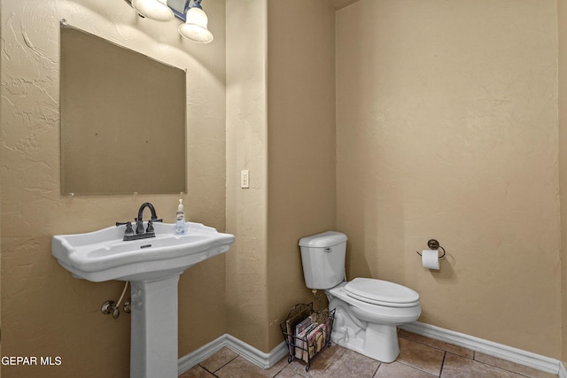 half bathroom featuring tile patterned floors, toilet, and baseboards