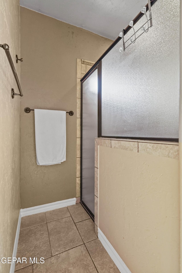 bathroom with tile patterned floors, an enclosed shower, and baseboards