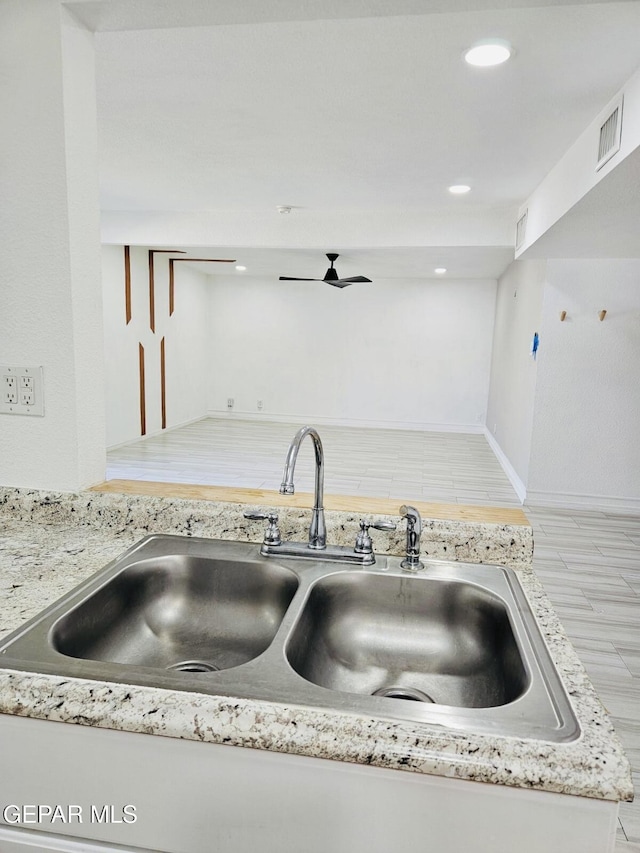 kitchen with light stone counters, baseboards, visible vents, recessed lighting, and a sink