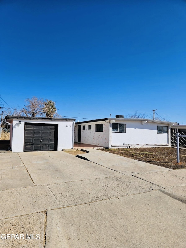 view of front of house with a garage, concrete driveway, and an outdoor structure