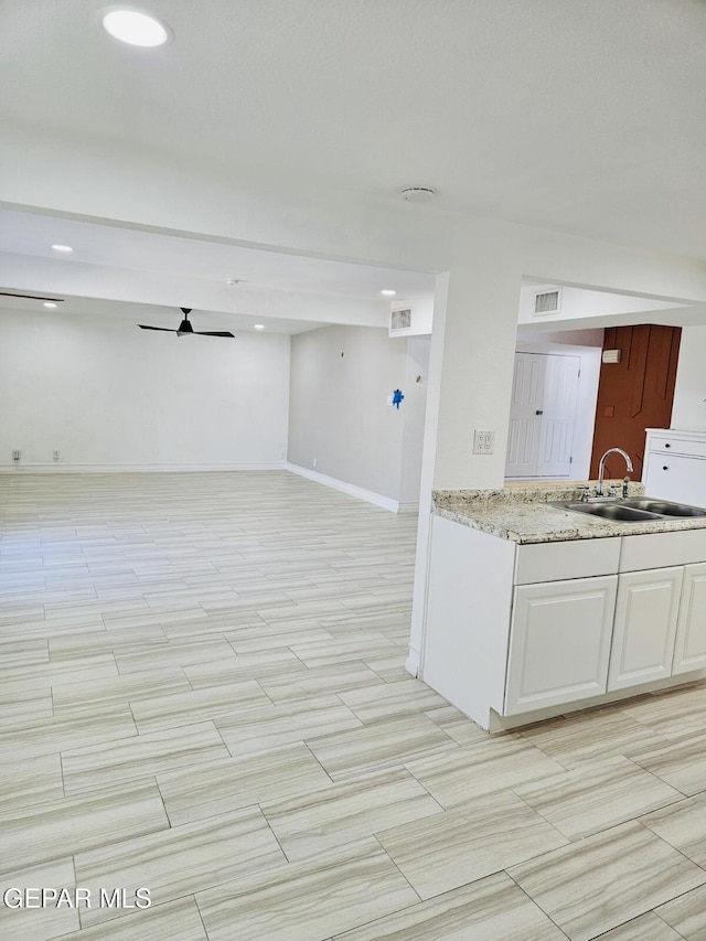 kitchen with visible vents, white cabinets, open floor plan, and a sink