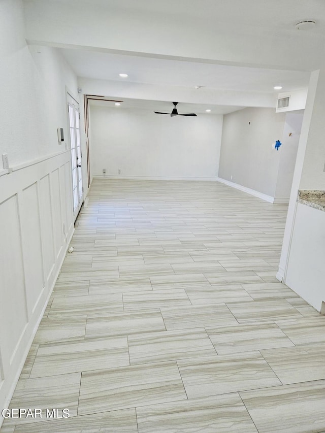 corridor with a decorative wall, visible vents, and a wainscoted wall