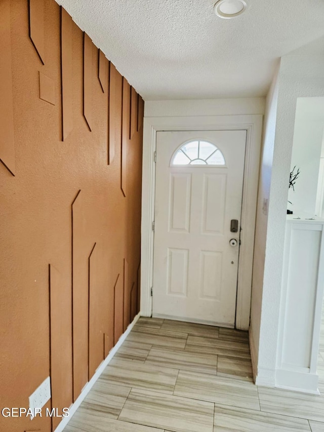 doorway to outside with a textured ceiling