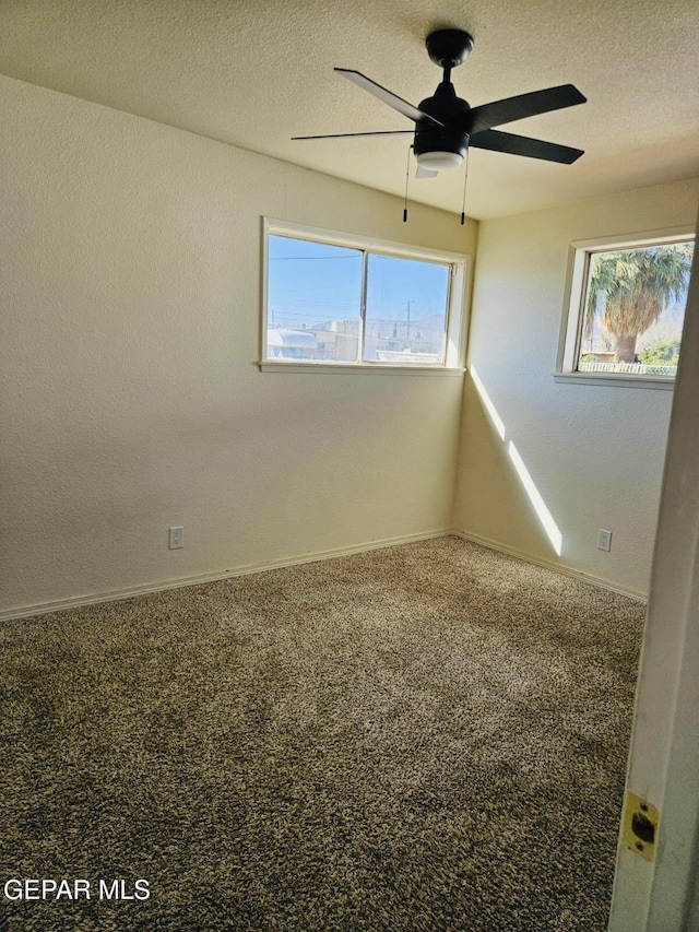 carpeted empty room featuring a textured ceiling, baseboards, and a ceiling fan