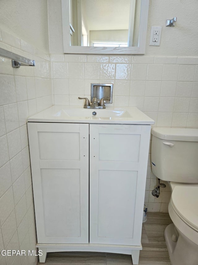 half bathroom with toilet, tile walls, and vanity