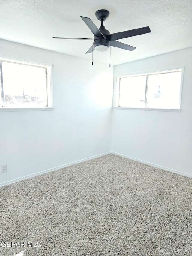 carpeted spare room with a ceiling fan, baseboards, and a textured ceiling