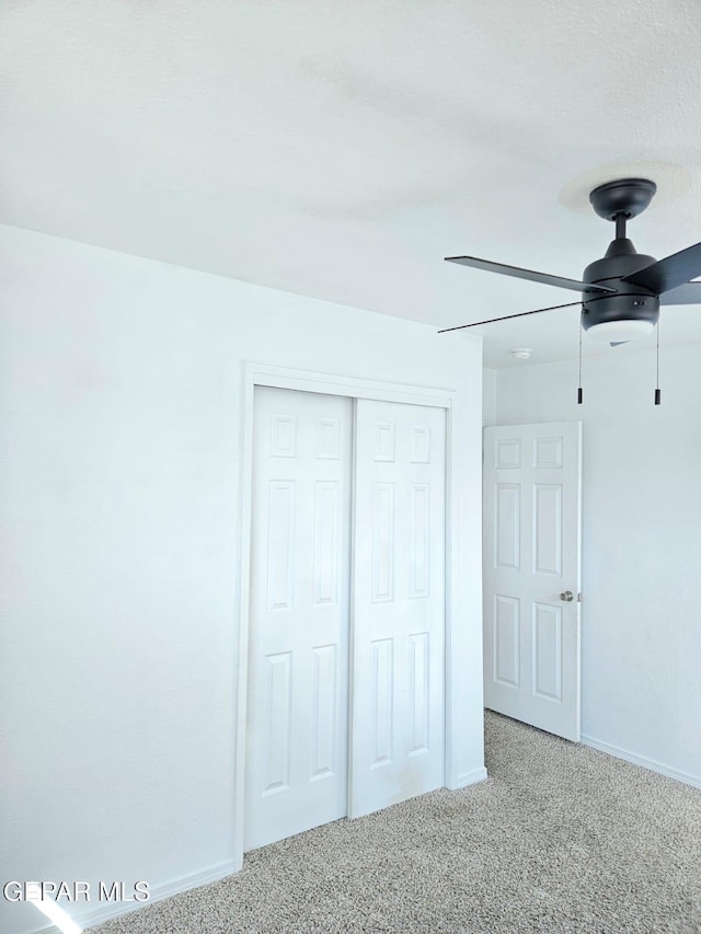 unfurnished bedroom with a closet, carpet floors, baseboards, and ceiling fan