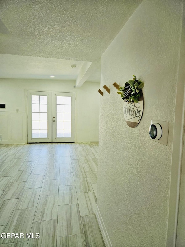 interior space with french doors, a textured wall, and a textured ceiling