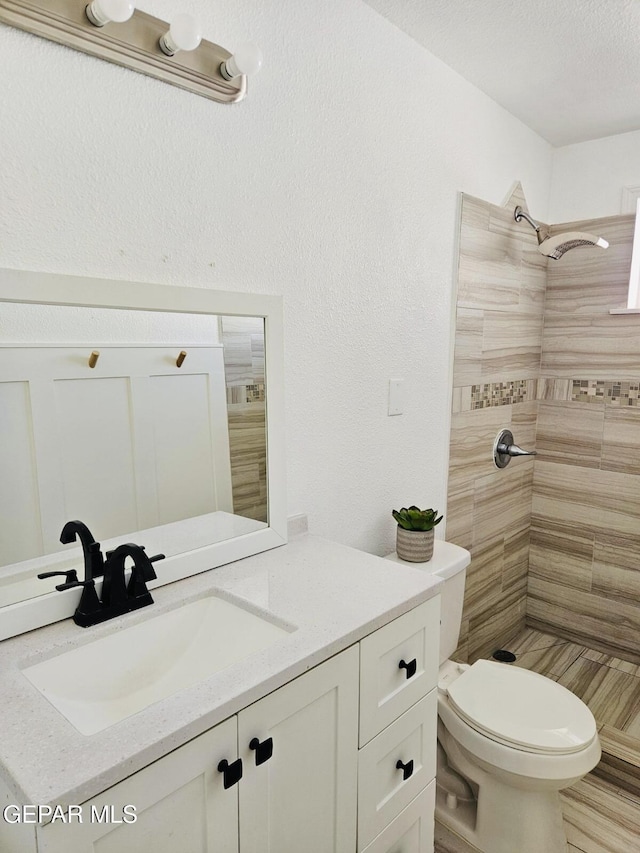 bathroom featuring vanity, toilet, and tiled shower