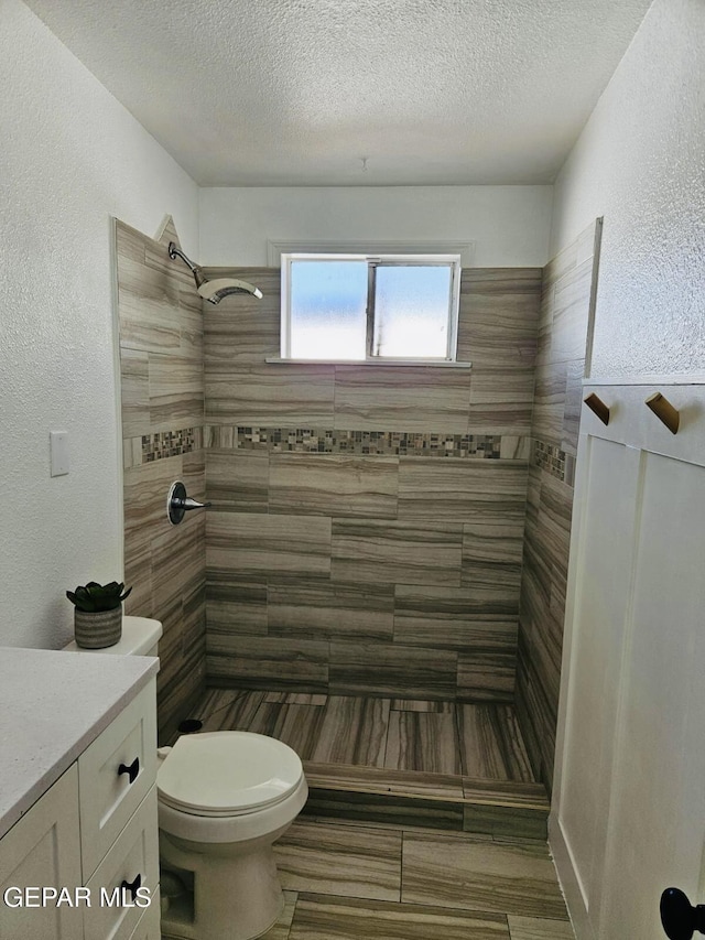 full bath with a textured ceiling, toilet, a textured wall, and tiled shower