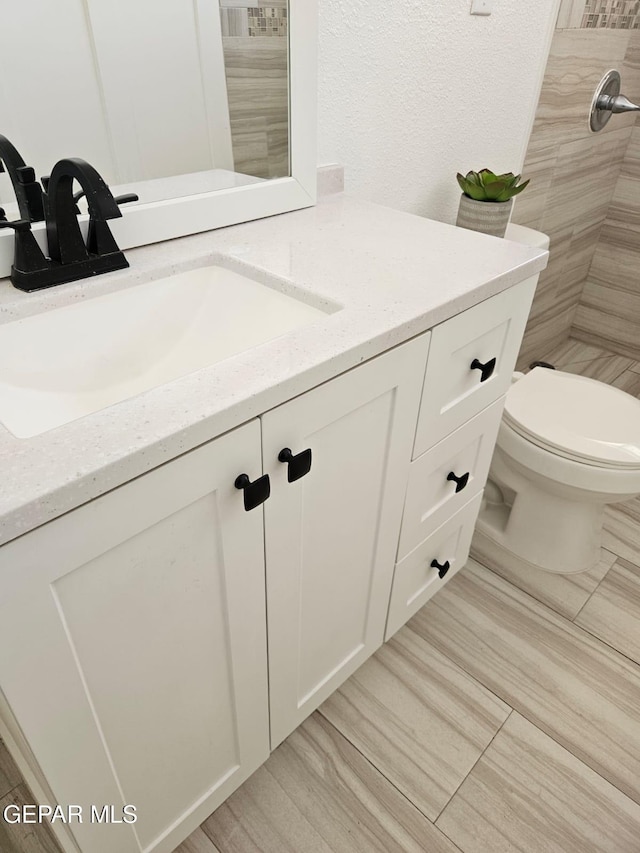 bathroom with vanity, toilet, and a tile shower