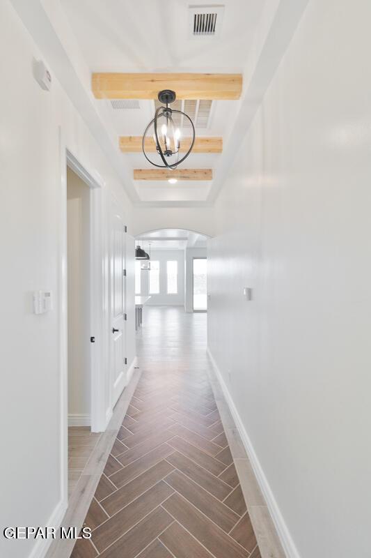 hall with visible vents, baseboards, arched walkways, and wood tiled floor