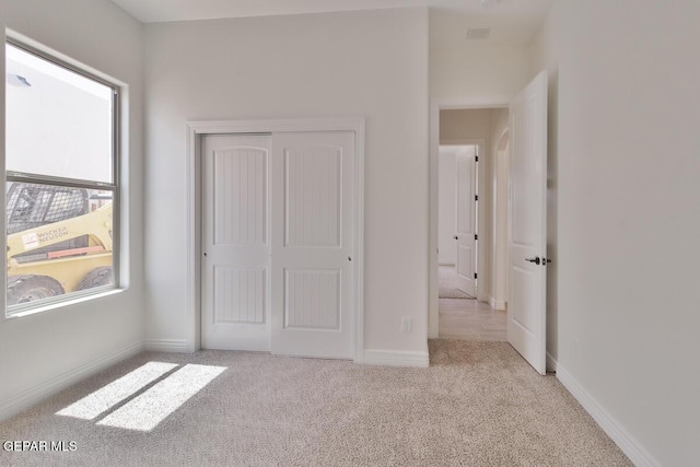 unfurnished bedroom with baseboards, a closet, carpet floors, and arched walkways