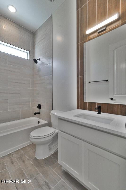 full bath with wood finish floors, vanity, toilet, and  shower combination