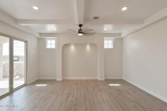 empty room with light wood finished floors, beam ceiling, and plenty of natural light