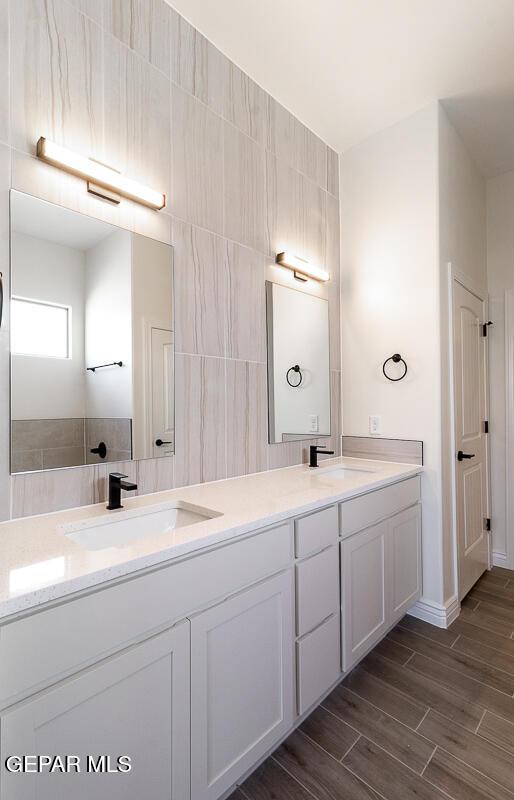 full bath with double vanity, wood finished floors, and a sink