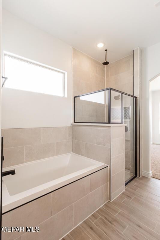 bathroom featuring wood tiled floor, a garden tub, and a shower stall