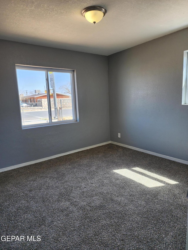 carpeted spare room with a textured ceiling and baseboards