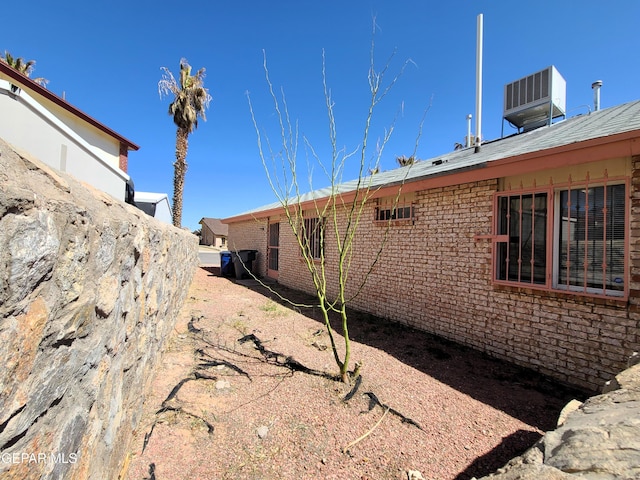 view of side of home with central air condition unit and brick siding