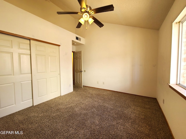 unfurnished bedroom featuring visible vents, lofted ceiling, a closet, a textured ceiling, and carpet flooring