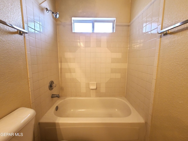 full bathroom featuring toilet, shower / bath combination, and a textured wall