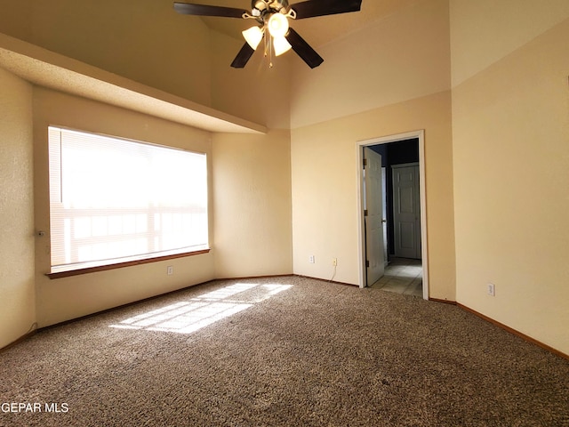 spare room with ceiling fan, a high ceiling, baseboards, and light carpet