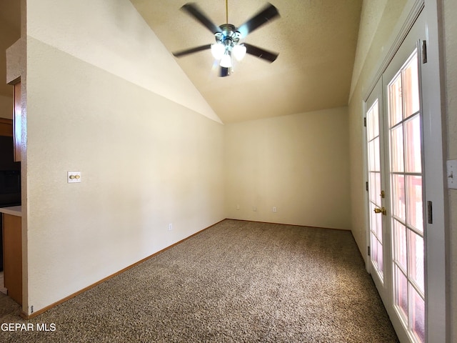 carpeted spare room with ceiling fan, baseboards, and vaulted ceiling