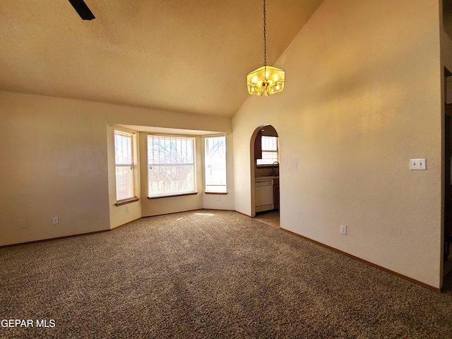 empty room with carpet, baseboards, high vaulted ceiling, arched walkways, and a notable chandelier