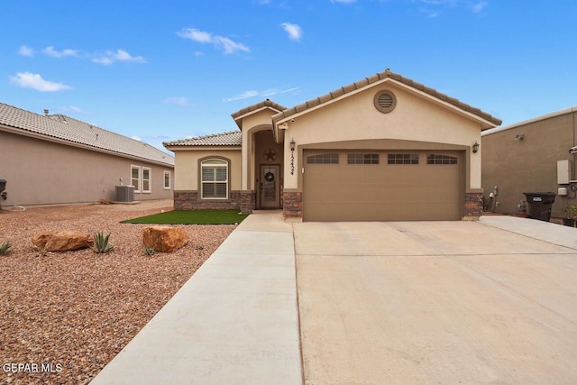 mediterranean / spanish home with concrete driveway, central AC, stucco siding, stone siding, and an attached garage