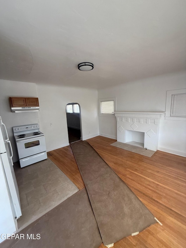 kitchen featuring electric range, brown cabinets, wood finished floors, fridge, and baseboards