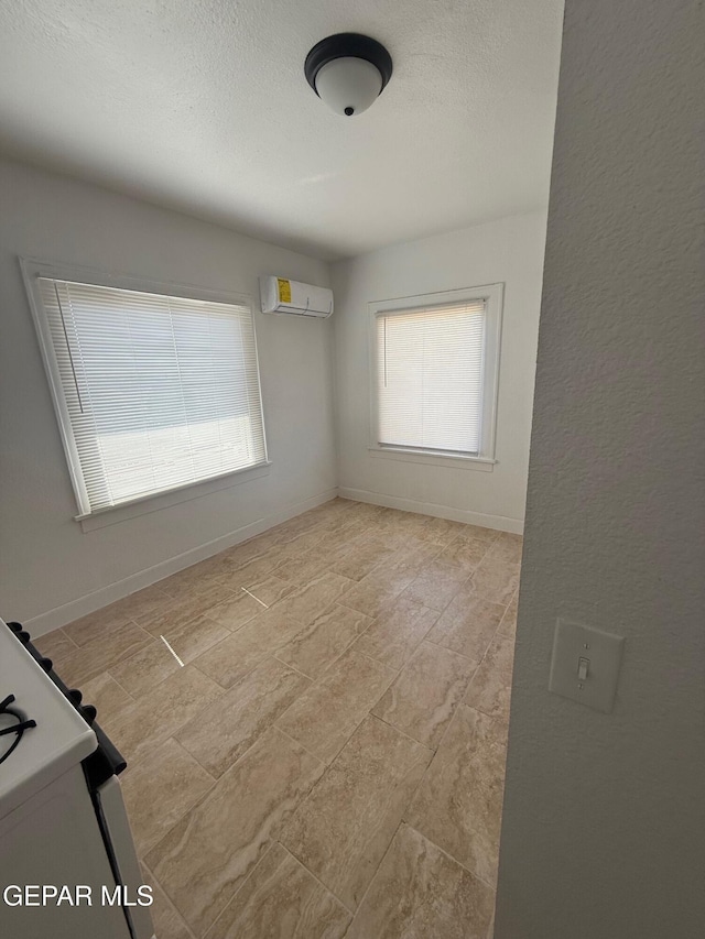 spare room featuring baseboards, a textured ceiling, and a wall mounted AC