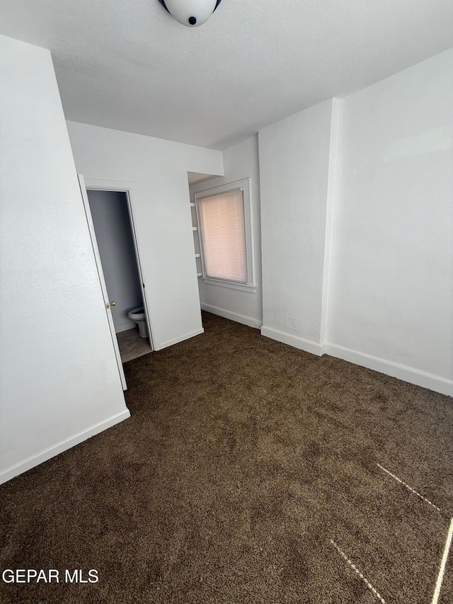 unfurnished bedroom featuring ensuite bathroom, baseboards, and carpet floors