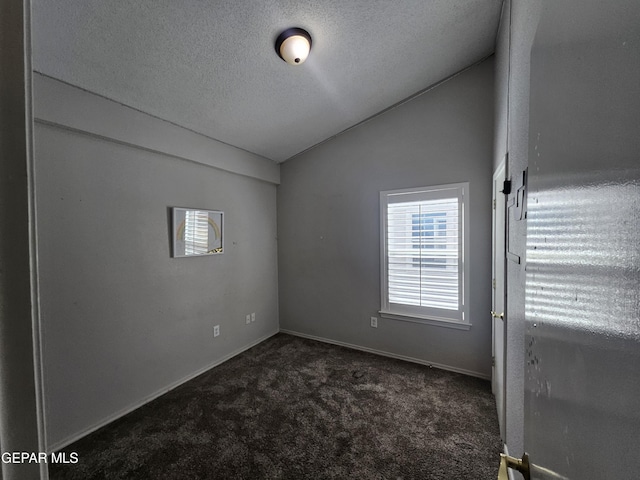 carpeted spare room with a textured ceiling, baseboards, and vaulted ceiling