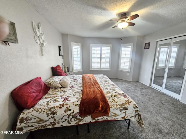 carpeted bedroom featuring ceiling fan, access to exterior, multiple windows, and a textured ceiling