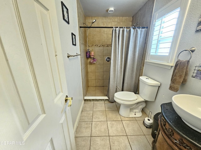 bathroom with tile patterned floors, baseboards, tiled shower, and toilet