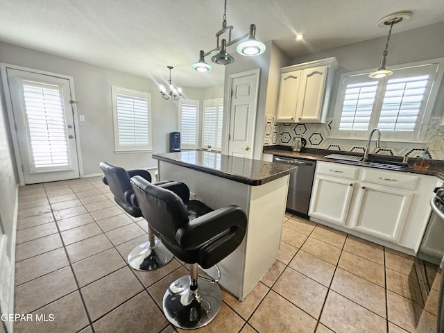 kitchen with a sink, stainless steel dishwasher, a center island, and light tile patterned floors