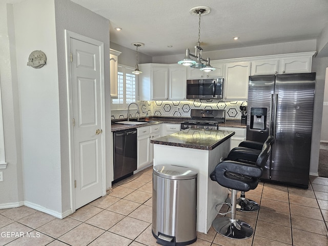 kitchen featuring a sink, stainless steel appliances, dark countertops, and white cabinetry