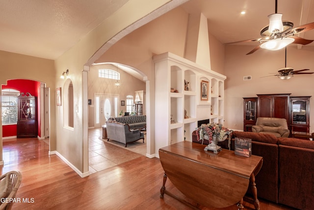 14097 Silver Spur St, El Paso, TX 79938 - living room with a ceiling fan, high vaulted ceiling, arched walkways, light wood-type flooring, and baseboards