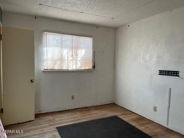 empty room featuring a textured ceiling and wood finished floors