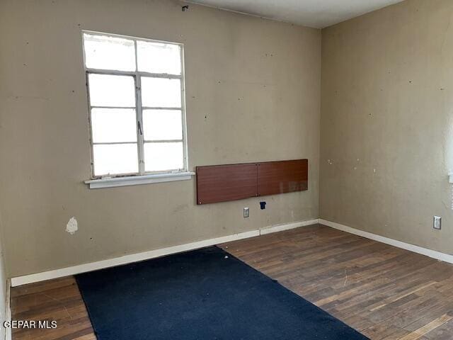 spare room with baseboards and wood finished floors