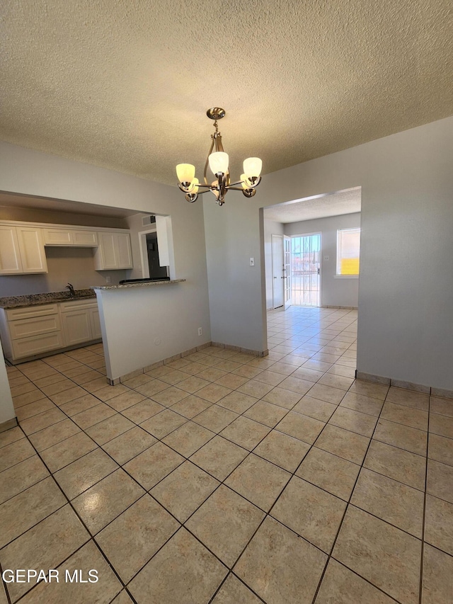 kitchen featuring white cabinetry, decorative light fixtures, light tile patterned floors, an inviting chandelier, and a textured ceiling