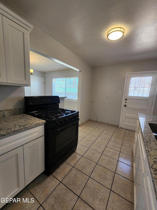 kitchen featuring light stone counters, a textured ceiling, white cabinetry, gas stove, and light tile patterned floors