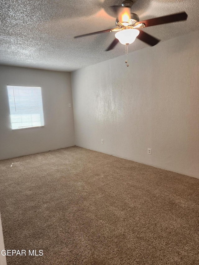 spare room featuring a textured ceiling, ceiling fan, carpet flooring, and a textured wall