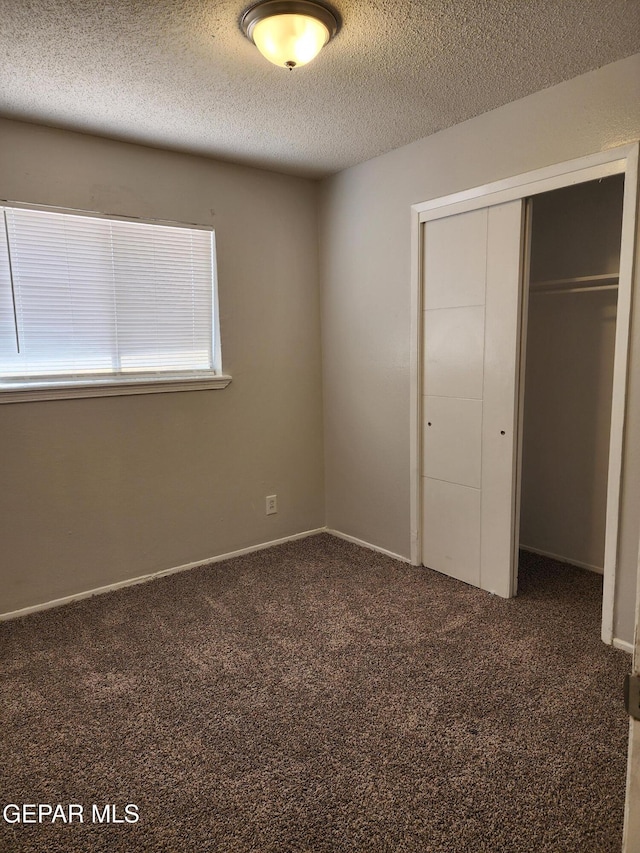 unfurnished bedroom with a closet, carpet floors, a textured ceiling, and baseboards