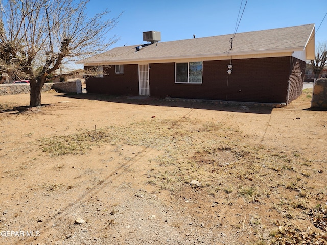 rear view of property with brick siding and central AC