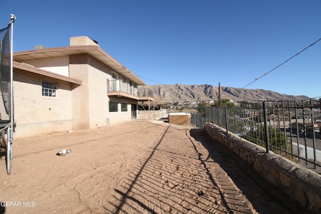 view of yard with a balcony, fence, and a mountain view