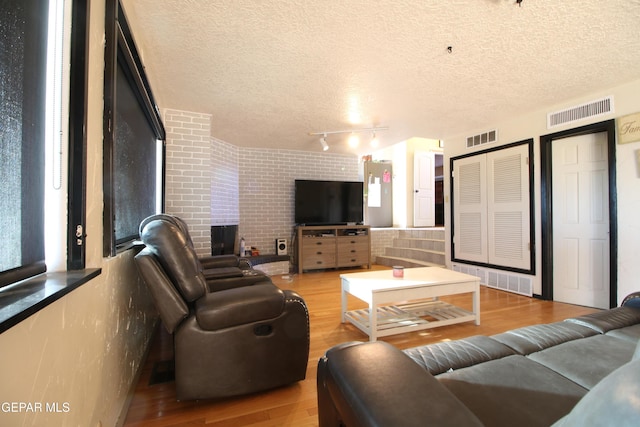 living room featuring a textured ceiling, a fireplace, visible vents, and light wood-type flooring