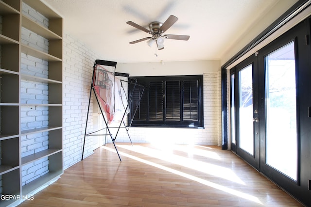 interior space with brick wall, french doors, wood finished floors, and access to outside